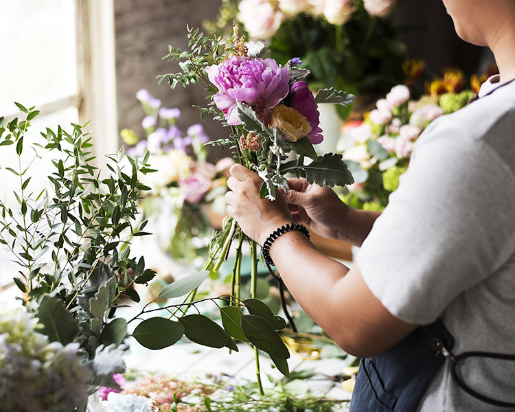 Pink and gold flowers are gently placed in a glass vase